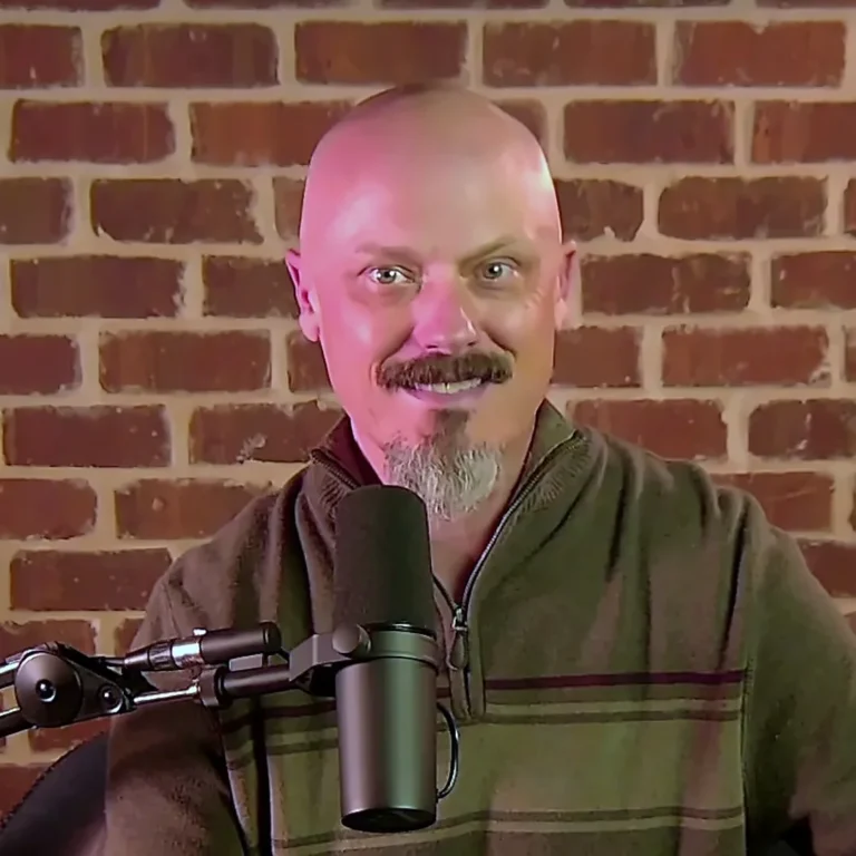Joe Watkins smiling at the mic in front of a brick wall