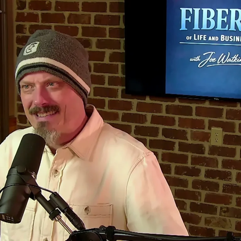 Joe Watkins laughing at the mic with the FIBERS logo behind him